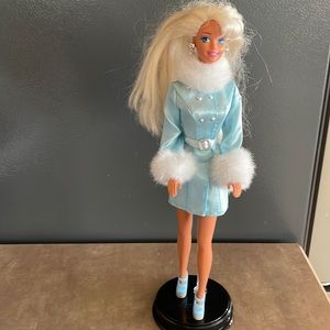 11.5” Barbie doll in a blue satin mini dress with silver and fur trim.